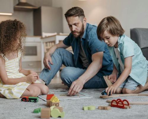 father with kids playing with toys on carpet