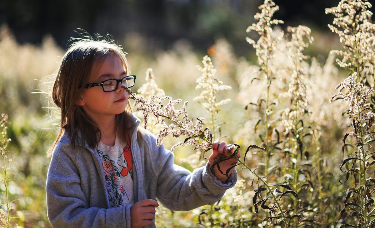 girl wearing eyeglasses smelling flowers