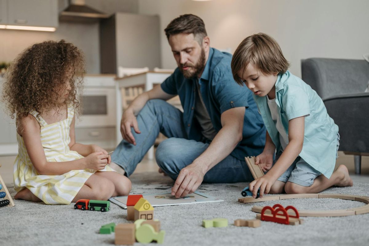 father with kids playing with toys on carpet