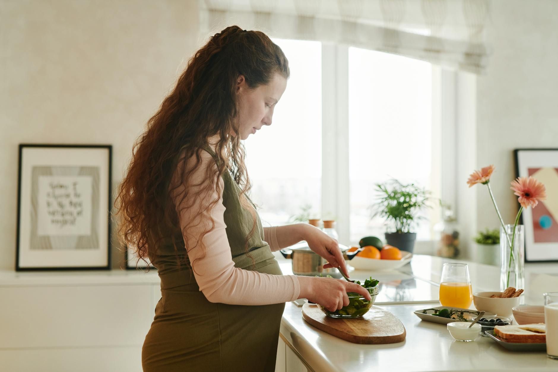 a pregnant woman preparing food on the kitchen counter a pregnant woman preparing food on the kitchen counter a pregnant woman preparing food on the kitchen counter