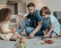 father with kids playing with toys on carpet