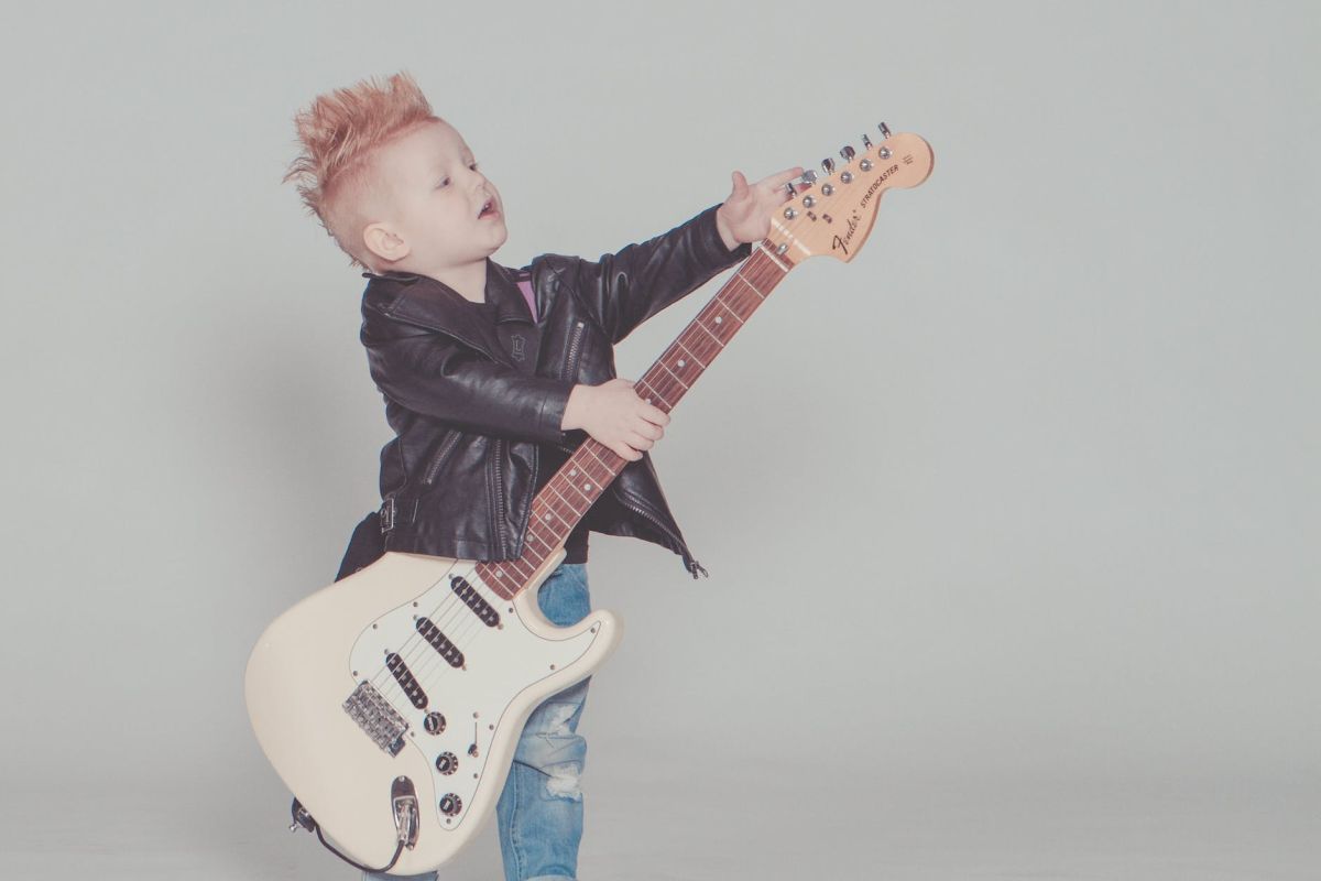 boy wearing black jacket holding electric guitar