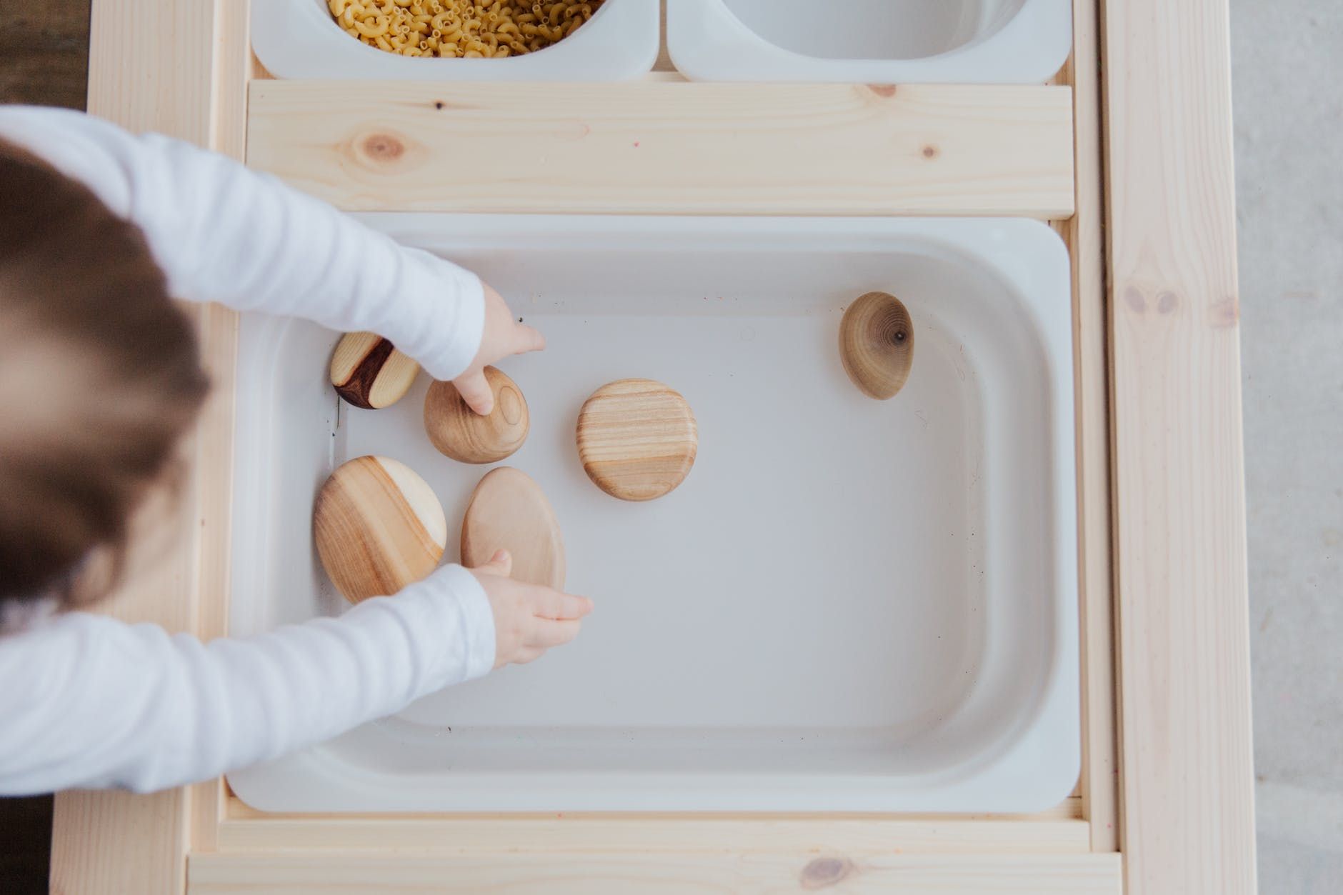 unrecognizable kid playing with stones in white container at table at home unrecognizable kid playing with stones in white container at table at home unrecognizable kid playing with stones in white container at table at home
