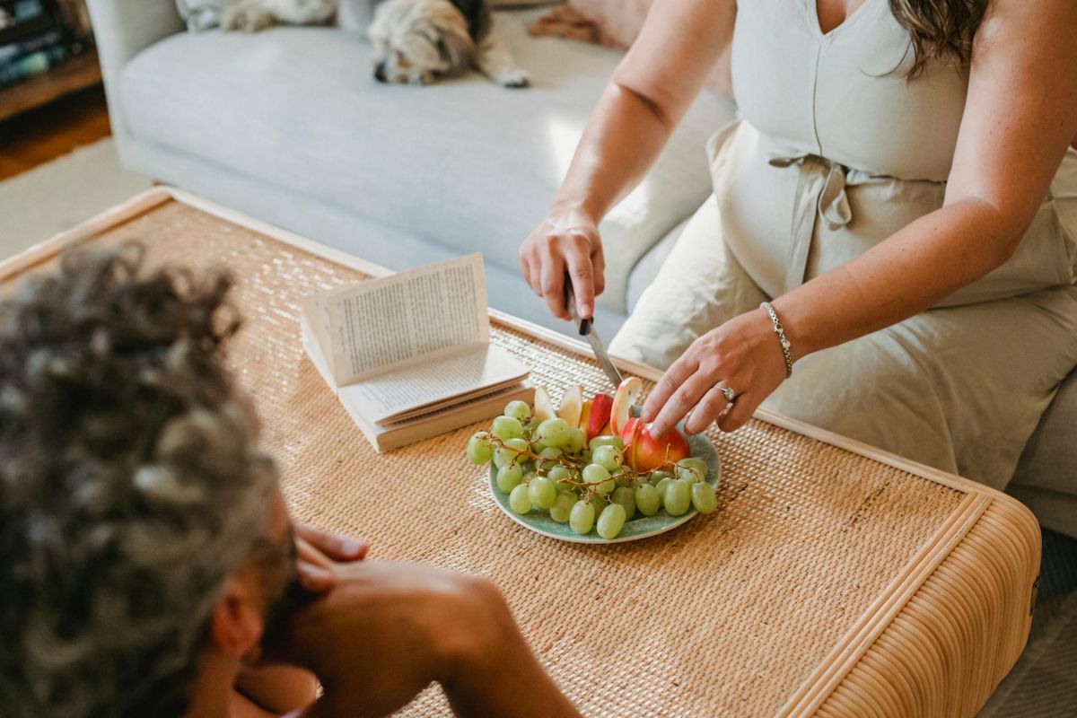 crop pregnant woman cutting fruit for husband